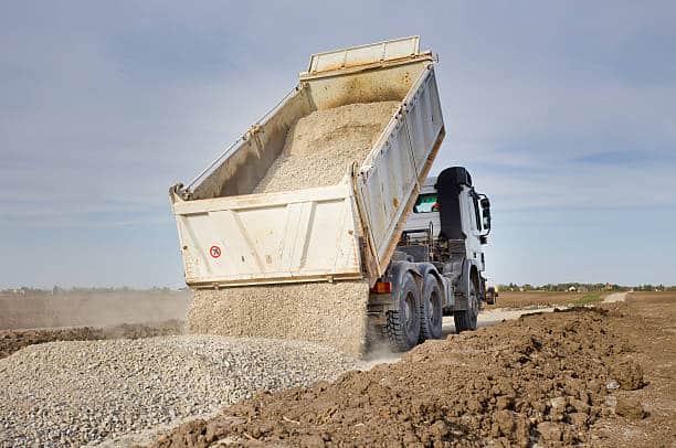 Tipping truck unloading gravel on road construction site tipper lorry